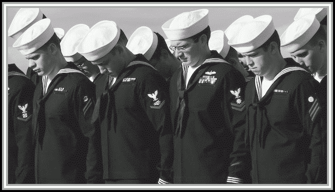 photograph of sailors with heads bowed in prayer.