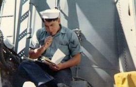 photograph of Ernie leaning up against the smoke stack reading at his work center 